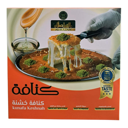 A boxed food product labeled 'Alsuftan Kunafa Keshnah' with a photo of cheesy baked pastries on the front, plus a gloved hand lifting a slice and a gold 'Taste Awards 2022' badge on the lower right.