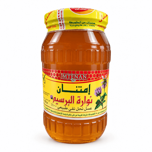 A glass jar of Imam Nan honey with a yellow label and a yellow lid, photographed on a clean white background.