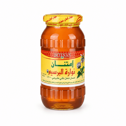 A glass jar of Imtenan Honey Rosem, filled with golden honey and featuring a yellow label with red and green text, set against a plain white background.