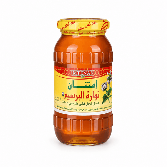 A glass jar of Imtenan Honey Rosem, filled with golden honey and featuring a yellow label with red and green text, set against a plain white background.